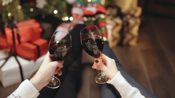 El vino para la Navidad y las celebraciones de Año Nuevo. Feliz pareja de beber copas de vino tostadas y celebrar juntos Nuevo 2022 Año en casa cerca de brillante árbol de Navidad. Enhorabuena concepto. — Vídeos de Stock