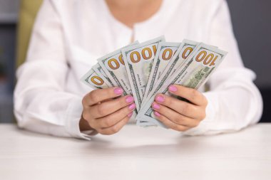 Stresli genç kadın aylık ev giderlerini hesaplıyor. Amerikan Doları 'nın faturalarını sayan ya da nakit ödeme yapan eller. Yatırım, başarı, finansal beklentiler veya kariyer ilerlemesi kavramı.