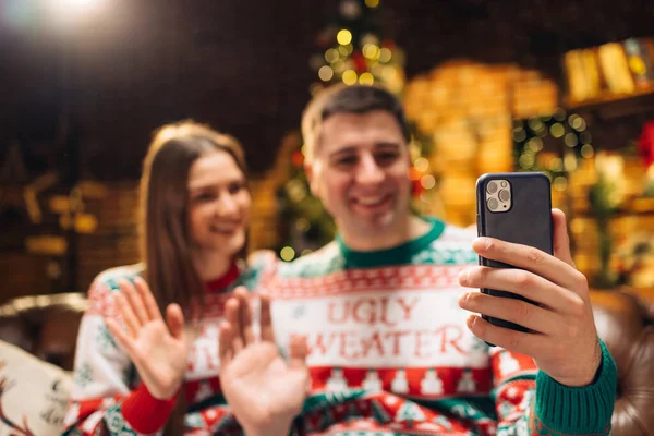 Mladý pár, který používá chytrý telefon a mluví s rodinou, blahopřeje Veselé Vánoce videokonferenční aplikací. Moderní technologie snadné a pohodlné použití, Nový 2022 Rok gratulujeme vzdáleně koncept. — Stock fotografie