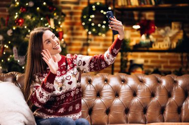 Kafkasyalı genç bir kadın akıllı telefon görüşmeleri yapıyor. Arkadaşlarıyla veya sevgilileriyle konuşuyorlar. Evdeki oturma odasında süslerle süslenmiş Noel ağacı. Noel ve Yeni Yıl bayramı festivali.