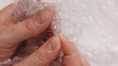 Gergin kadın stresi azaltmak için plastik balonlu naylona basıyor. Kabarcık ambalajı. Kadınların elleri kabarcık kağıdına sıkışıyor.