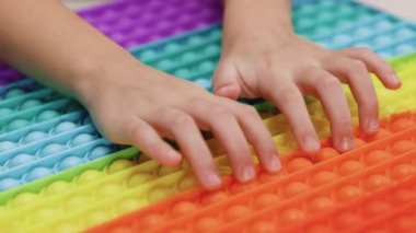 Çocuklar için bir oyun. Endişeli çocuklar için renkli bir oyuncak. Antidepresan oyuncak baloncukları patlatıyor. Parmaklar baloncuklara bastırıyor, popüler anti-stres oyuncağı patlıyor..