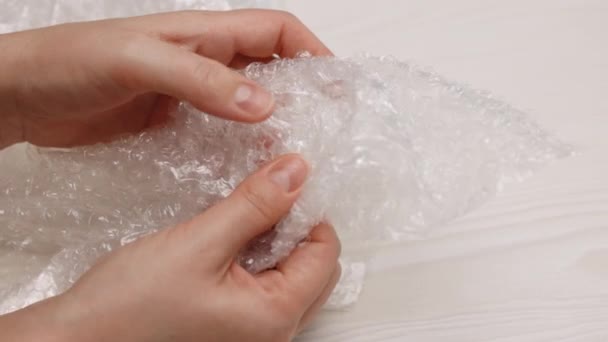 Woman presses a bubble wrap. Female hands burst air bubbles on a bubble wrap on a white background. Calming the nervous system concept. — Video Stock