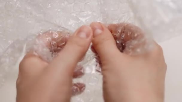 Hand under pressure crushes popping the bubble wrap. Fingers popping bubbles in bubble wrap close-up anti-stress therapy during quarantine and lockdown — Vídeo de Stock