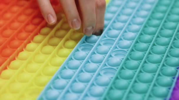 Finger presses bubbles on childrens popular anti-stress toy pop it. Woman presses on the pimples of a popular colorful toy pop it, a childrens silicone anti-stress toy. — Video Stock