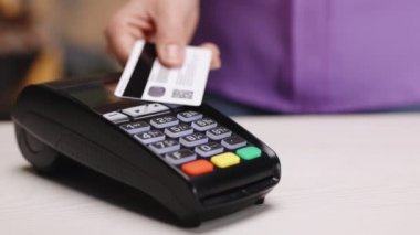 NFC teknolojisiyle çalışan bir kadın kredi kartıyla ödeme yapıyor. NFC kredi kartı ödemesi. Kablosuz para transferi. Kablosuz ödeme. Nakitsiz cüzdanda e-para