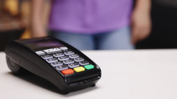 Female hands with pos-terminal of employee and cellphone closeup. Pay by phone on electronic payment machine or card reader. Client buys food order at coffee place. E-money at cashless wallet — Stockvideo