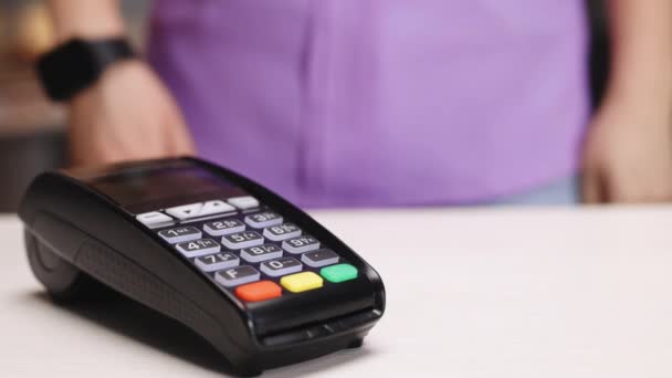 Pagar con reloj inteligente en la máquina de pago electrónico o lector de tarjetas. Dinero electrónico en una billetera sin efectivo. Cliente femenino mano en pos-terminal de vendedor o empleado de tienda en cafetería o supermercado de alimentos — Vídeo de stock