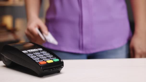 Close up of woman hands making payment with credit card machine terminal while swiping debit card to pay the bill. NFC credit card payment. Wireless money transaction — Stock Video