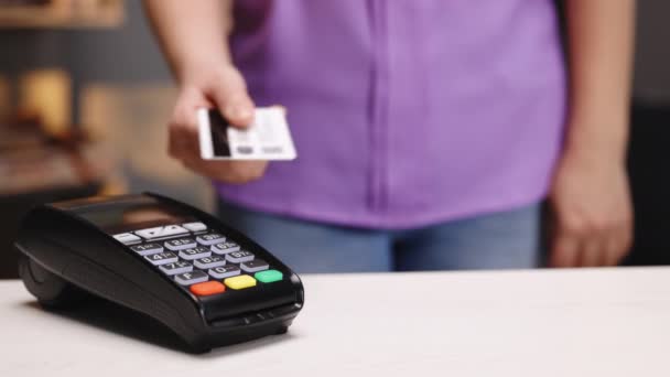 Tecnología NFC. Primer plano de la joven mujer caucásica usando tarjeta de crédito con chip NFC en la terminal bancaria. Cliente que paga por pedido de alimentos al aire libre — Vídeo de stock