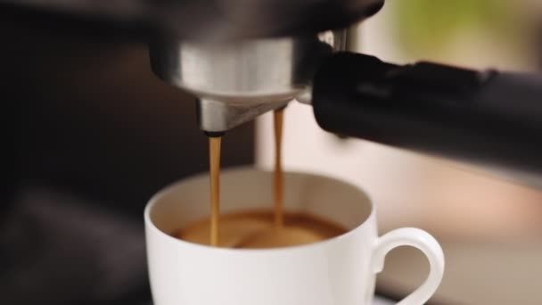 Κάνοντας καφέ espresso ή ristretto στη μηχανή του καφέ. Το σπίτι φτιάχνει καυτό εσπρέσο. Καφέ με αφρό. Εσπρέσο σε λευκό κύπελλο. Νόστιμο καφέ. Καφεΐνη. — Αρχείο Βίντεο