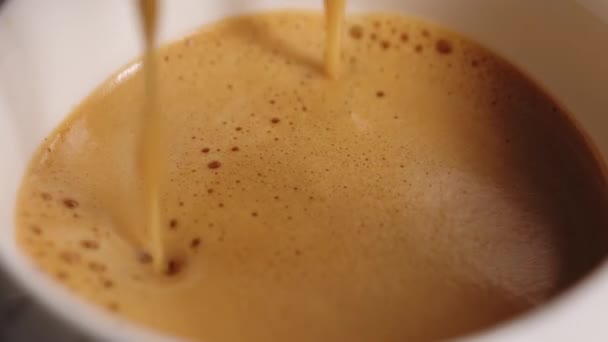 Falling drop into coffee cup. Drop falls into a cup of coffee with milk with splashes. Slow motion of pouring milk into coffee drink — Vídeo de Stock