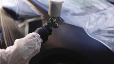 Manüel püskürtme makinesinin araba boyası ile yakın plan görüntüsü metal boyası. İşçi araç hizmet merkezinde ekipman tutuyor ve yönetiyor. Modern araba boyama