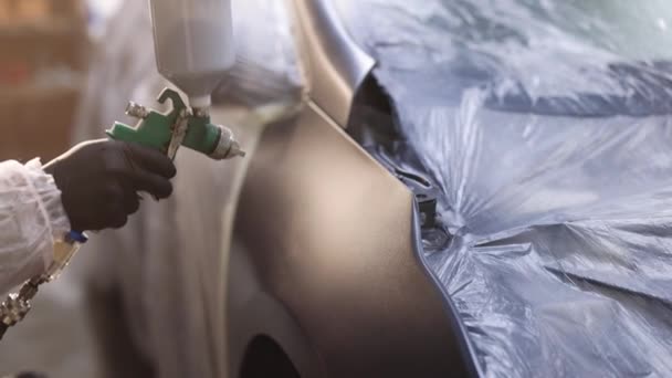 Verniciatura Spray Vernice parti del veicolo presso l'officina di assistenza auto. Processo di verniciatura industriale a spruzzo. Un uomo che dipinge un'auto in una carrozzeria. Fabbrica di produzione auto — Video Stock