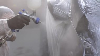 Adam Sprey Silahla Parça Boyuyor. Tamirci, Endüstriyel Boya Spreyi Kullanarak Araba Boyuyor. Usta araba servisinde otomobilin bir parçasını boyuyor.