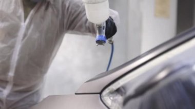 Fabrika boyama tesisinde sanayi boyama işlemi. Erkek teknisyen hava temizleyici metal elementler. Boya teknisyeni sprey tabancayla arabanın bir parçasını boyuyor. Endüstriyel sprey boya işlemi.