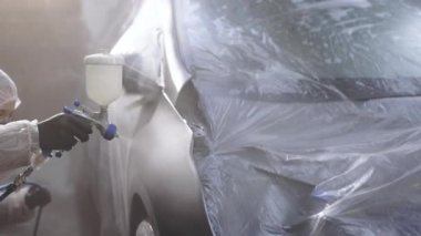 Erkek teknisyen araba boyama kanadında. Endüstriyel sprey boya işlemi. Siyah renkli araba. Usta araba servisinde otomobilin bir parçasını boyuyor.