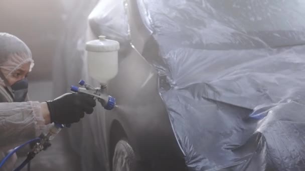 De man draagt een beschermend uniform schilderij Spray Paint voertuigonderdelen in de garage. Industrieel spuitverfproces. Autofabriek — Stockvideo