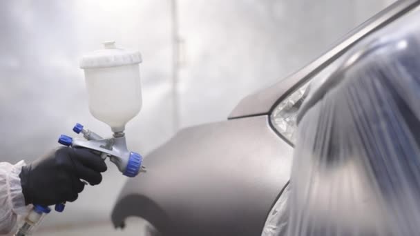 Male Worker In Full Protective Suit And Face Mask Holding Spray Paint Car Parts. Auto painter spraying of the car in special booth. Painting vehicle parts at car service workshop — Stock Video