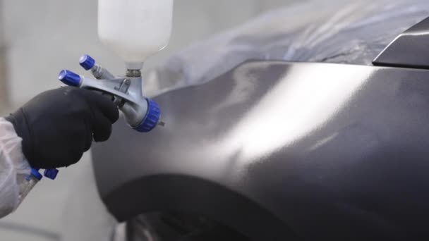 Primer plano de los trabajadores masculinos en el desgaste de seguridad durante la pintura de coches. Proceso de pintura industrial en las instalaciones de la fábrica de pintura. El hombre técnico es ala de coches de pintura al aire — Vídeos de Stock