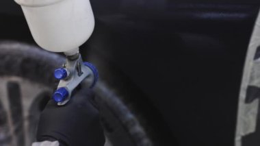 Araba boyarken güvenlik görevlisi erkek işçilere yakın çekim. Fabrika boyama tesisinde sanayi boyama işlemi. Erkek teknisyen araba boyama kanadında.