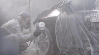 Otomobil boyacısı özel bölmede siyah boya püskürtüyor, yavaş çekimde. Araba servisi atölyesinde araç parçaları boyuyorum. Araba üretim fabrikası