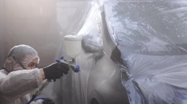 Boyacı, özel bölmede arabanın kapısına kırmızı boya sıkıyor, ağır çekimde. Araba servisi atölyesinde araç parçaları boyuyorum. Erkek teknisyen hava boyalı araba kapısı. Endüstriyel sprey boya işlemi