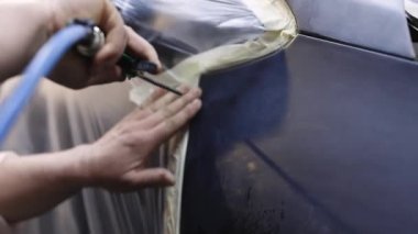 Ressamın yakın çekimi araba gövdesini boyamaya hazırlar. Arabanın gövdesini öğütüyorum. Tamirci arabanın gövdesini boyamaya hazırlıyor.