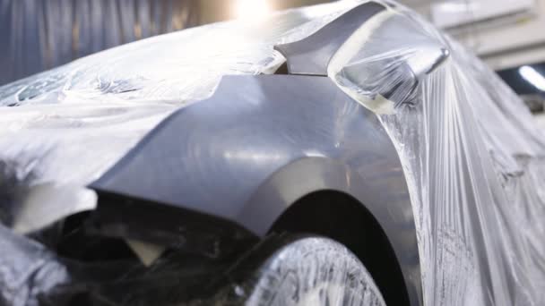 El ala negra del coche está preparada para pintar. Cuerpo del coche para pintar. Pintar la carrocería de un vehículo en una fábrica de fabricación de automóviles. Preparando el coche para la pintura y cubriendo las partes del cuerpo. — Vídeo de stock