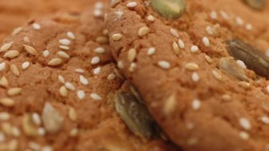 Beyaz arka planda kahverengi kurabiyeler. Beslenme kurabiyelerine buğday düşer. Yulaf ezmeli kurabiye ye. Masada susamlı yulaflı kurabiye rotasyonu. Cips kurabiyesi yapma kavramı