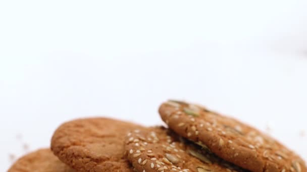 Bolachas no fundo branco. Comida, conceito de comer. Biscoitos com pedaços de sementes de abóbora de girassol, rotação. Coma biscoitos de aveia — Vídeo de Stock