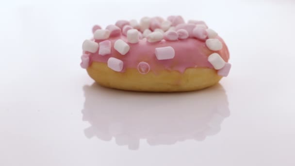 Lekker roterende donut op witte achtergrond. Roterende close-up shot van roze smakelijke zoete donut met kleurrijke hagelslag op witte achtergrond. Het dessert. Kleurrijke frosted roze donut — Stockvideo