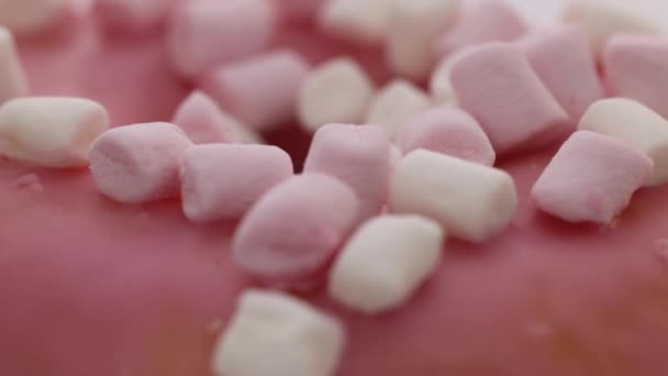 Close-up shot van roze smakelijke zoete donut met kleurrijke hagelslag op paarse achtergrond. Het dessert. Kleurrijke frosted roze donut. — Stockvideo