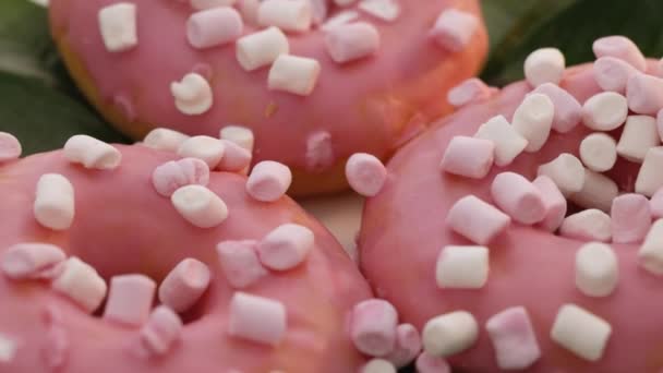 Donuts de cobertura rosa em um fundo branco. Sobremesa. padaria e confeitaria. Rotativa close-up de saborosos deliciosos donuts de pães doces com cobertura colorida e polvilhas — Vídeo de Stock