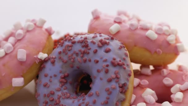 Roterende close-up shot van heerlijke zoete broodjes donuts met kleurrijke glazuur en hagelslag. Dessert, bakkerij en zoetwaren. Lekker roterende donuts. Assortiment van donuts van verschillende smaken. — Stockvideo