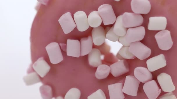 Close-up of pink donut on a white plate rotates. Sweet snacks baking. Sweet high-calorie food. Favorite donuts for kids. Donut cake for breakfast. Selective focus, shallow depth of field — Stock Video