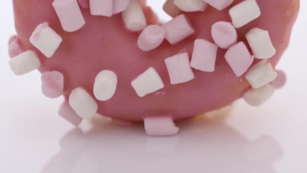 분홍색 도넛에 있는 분홍색 과 흰색 마시멜로를 닫고 달콤 한 디저트 사탕 맛있는 설탕을 넣는다. 달콤 한 도넛 디저트에 핑크 유약을 클로즈업해서 — 비디오