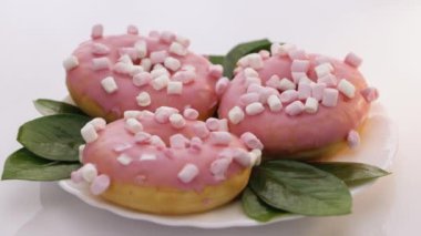 Renkli, buzlu, pembe çörek. Çeşitli çörekler. Pembe jöleli ve şekerli çörekler. Beyaz arka planda renkli serpiştirilmiş beyaz lezzetli tatlı çöreğin dönüşümlü görüntüsü. Tatlı.