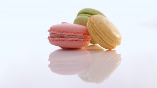 Los macarrones giran sobre fondo blanco. Tres galletas macarrones se apilan uno encima del otro. Macarrón tradicional francés multicolor. Concepto alimenticio. — Vídeos de Stock