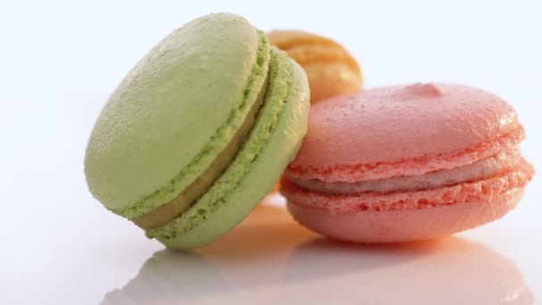 Traditionele Franse veelkleurige makaron. Macarons draaien op een witte achtergrond. Drie koekjes macarons worden op elkaar gestapeld. Voedselconcept. — Stockvideo