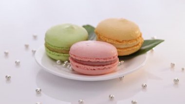 Beyaz tabakta dönen renkli badem kurabiyeleri. Makarna tatlısı. Pastel rengarenk, değişik renklerde makaron çeşitleri. Yüksek kalite 4k görüntü