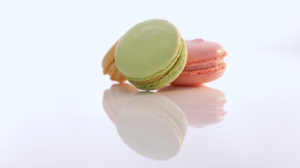 I macaron ruotano su sfondo bianco. Tre biscotti macaron sono impilati uno sopra l'altro. Macaron multicolore tradizionale francese. Concetto alimentare. — Video Stock