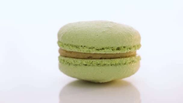 Kleurrijke cake macarons geïsoleerd op abstracte achtergrond. Groene macaron gebakjes draaien op een witte achtergrond. Traditionele Franse veelkleurige makaron. Voedselconcept. — Stockvideo