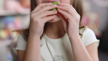 Yakından bakınca tanınmayan esmer kız fıstıklı, yeşil makaronlu kurabiyeyi ısırıyor. Lezzetli, tatlı bir makaron. Geleneksel Fransız çok renkli badem kurabiyesi. Yiyecek konsepti