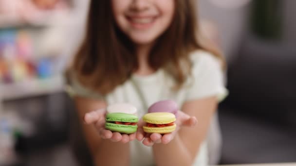 Kameraya uzanan iki lezzetli bademli kurabiyeyle ellerini uzatan, ağzı gülümseyen sevimli kız. Kurabiyelere odaklan. İyi hissediyorum, lezzetli.. — Stok video