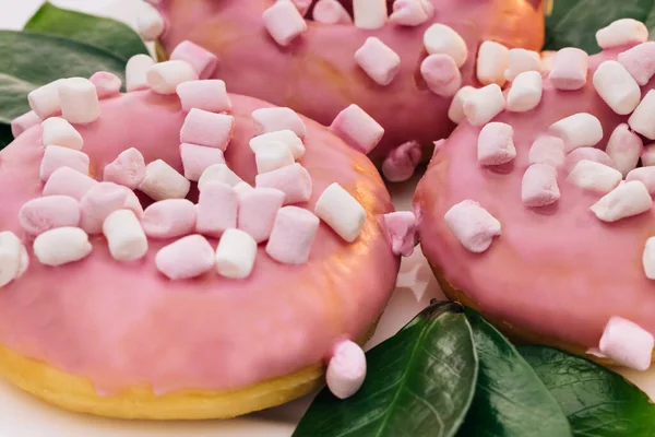 Крупный план вкусных круглых пончиков, покрытых сладкой глазурью, вращается на ярком фоне. Сладкий десерт розовые пончики — стоковое фото