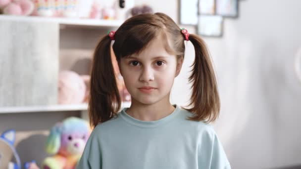 Portret van een schattig klein meisje is blijdschap en toont haar verloren melktand en glimlacht naar de camera van tandeloze mond terwijl ze in de slaapkamer staat. gelukkig meisje houden haar gevallen tand in de hand. — Stockvideo
