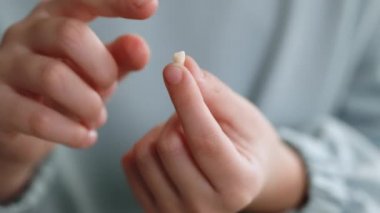 Küçük kız süt dişlerini döküyor. Süt dişli küçük kız. Çocuk dişini elinde tutuyor. Diş hekimliği veya geçici diş sağlığı konsepti