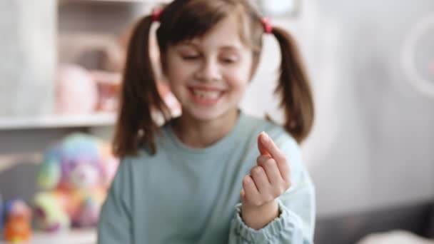 Potret seorang bayi perempuan dengan senyum ompong. Menunjukkan gigi robek ke kamera dengan tangan yang panjang. Fokus pergeseran dari gigi ke muka. Obat gigi atau konsep perawatan gigi sementara — Stok Video