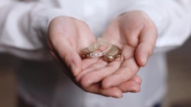 İşitme cihazı taşıyan genç bayana yakın çekim. Beyaz arka planda işitme cihazı taşıyan bir kadın. İşitme cihazı dişinin avucunda. İşitme cihazı konsepti